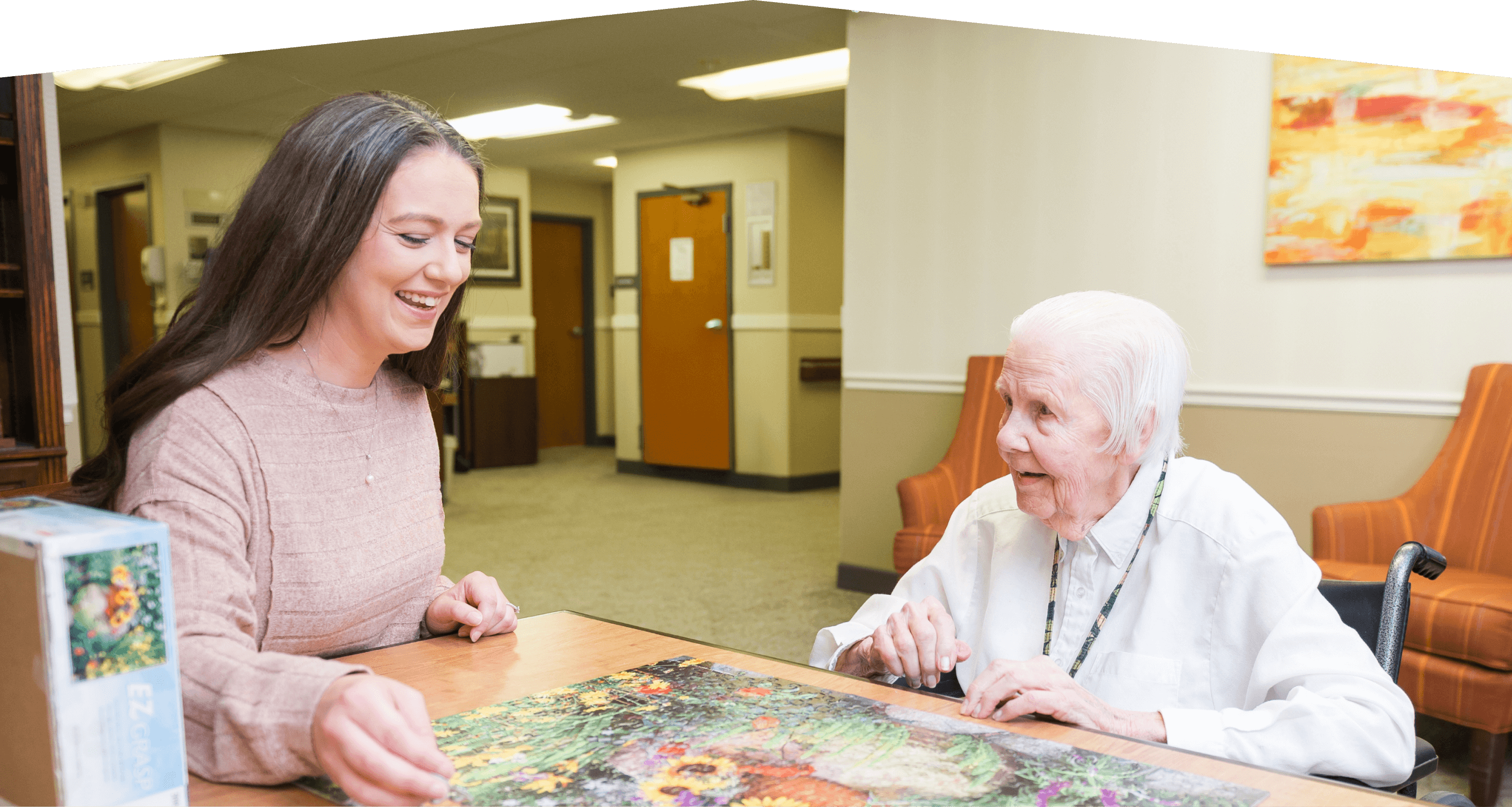 Woman doing a puzzle with resident.